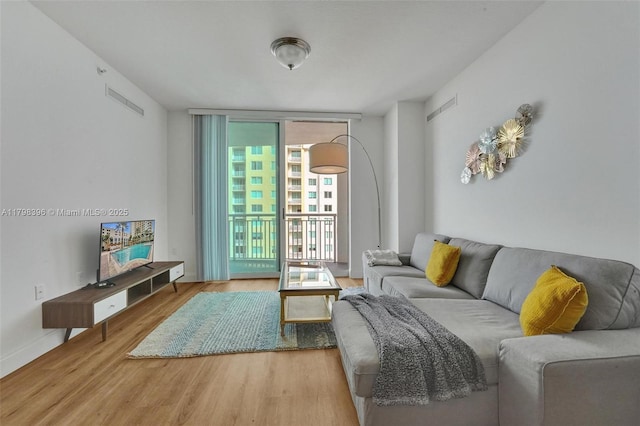living room featuring wood finished floors, expansive windows, and baseboards