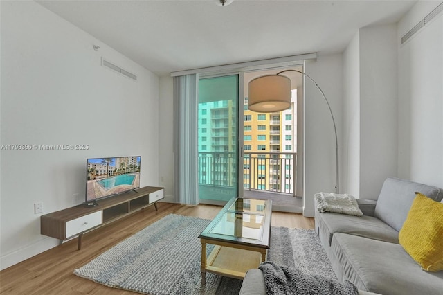living area with expansive windows, wood finished floors, and baseboards