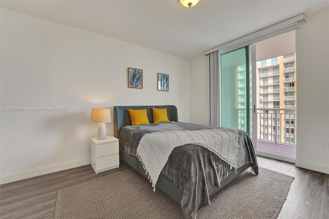 bedroom with wood finished floors, baseboards, and access to exterior