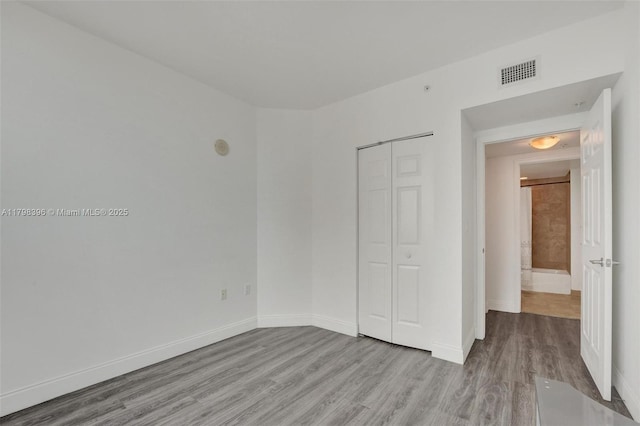 unfurnished bedroom featuring light wood-style flooring, a closet, and baseboards