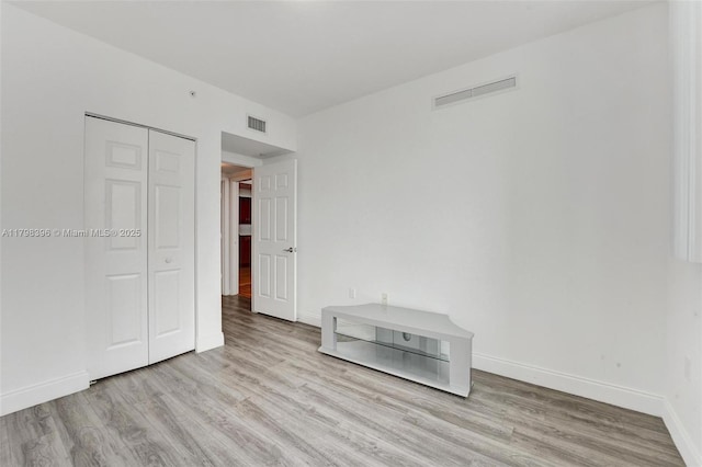 unfurnished bedroom with wood finished floors, baseboards, and a closet
