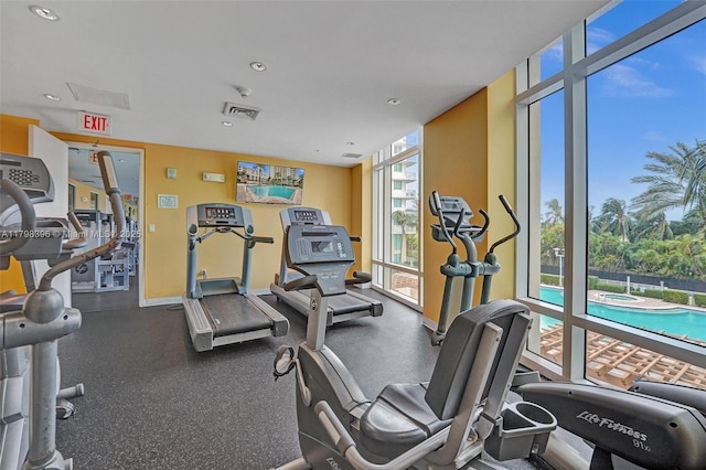 gym with floor to ceiling windows and recessed lighting