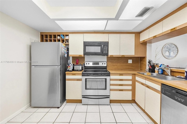 kitchen with appliances with stainless steel finishes, a sink, light countertops, and backsplash