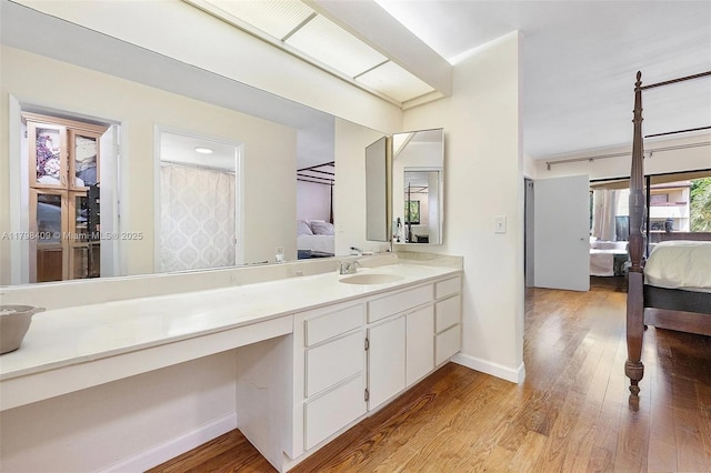 ensuite bathroom featuring wood finished floors, baseboards, and vanity