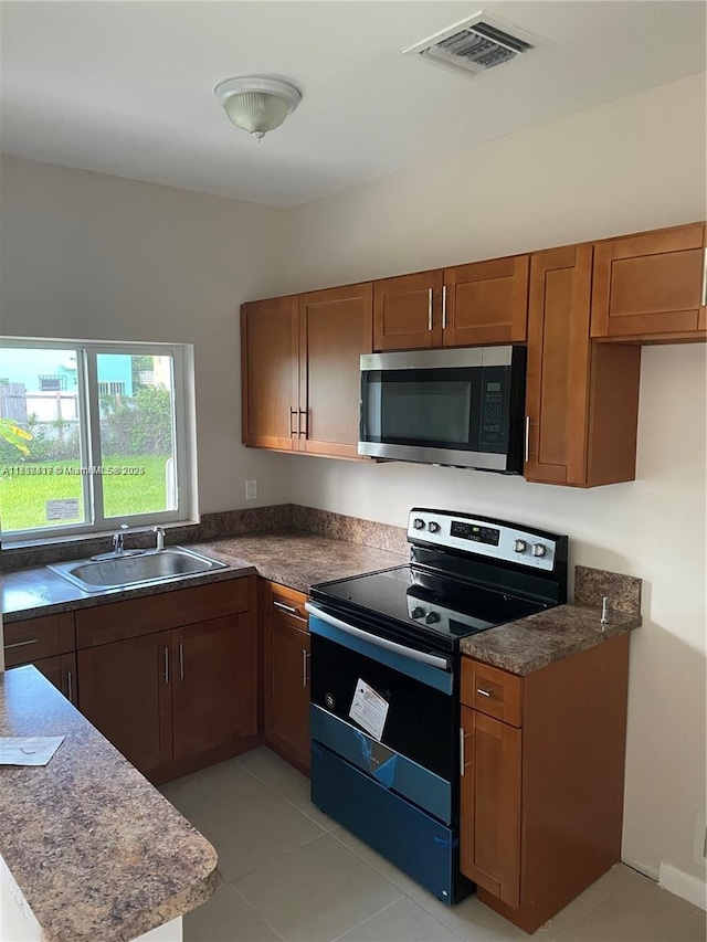 8321 NE Miami Ct, Miami, FL 33138 - kitchen featuring stainless steel microwave, electric stove, a sink, dark countertops, and brown cabinetry