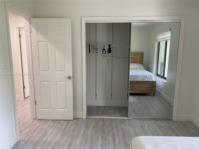 bedroom featuring baseboards, wood finished floors, and a closet