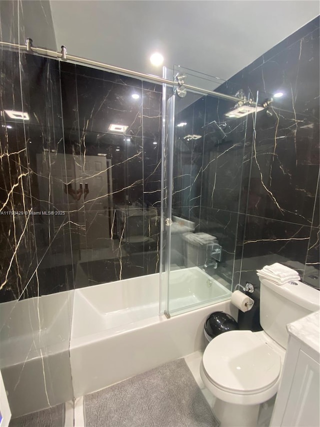 bathroom with toilet, combined bath / shower with glass door, tile walls, and vanity