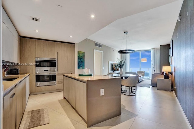 kitchen with double oven, modern cabinets, a center island, light countertops, and expansive windows