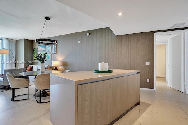 kitchen with a kitchen island, light tile patterned flooring, light countertops, light brown cabinets, and modern cabinets