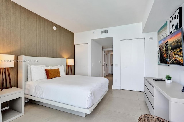 bedroom featuring light tile patterned floors and an accent wall