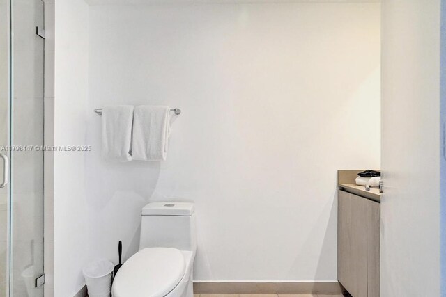 full bathroom with toilet, baseboards, and a shower with shower door