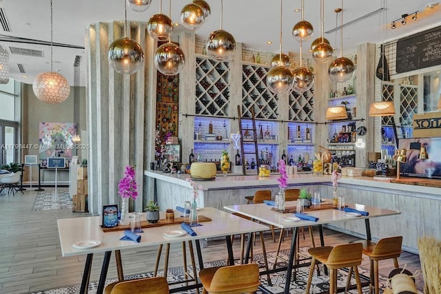 bar area featuring wood finished floors, a towering ceiling, and pendant lighting