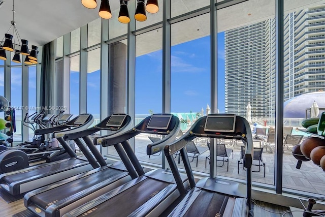gym with floor to ceiling windows and a chandelier