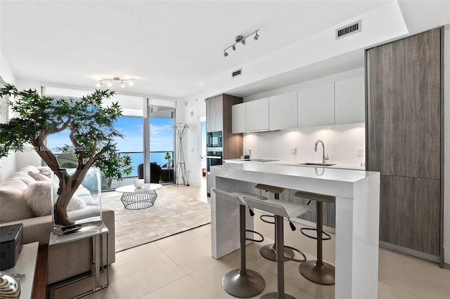kitchen with a sink, modern cabinets, black appliances, and rail lighting