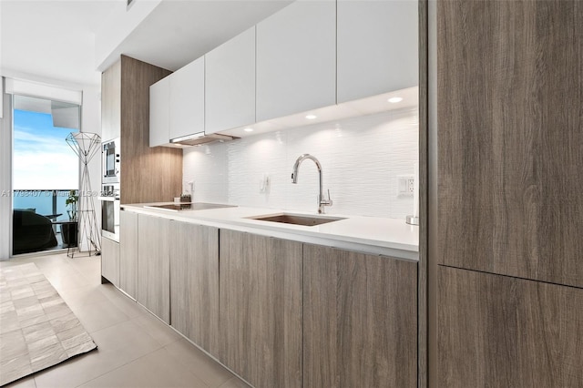 kitchen featuring a sink, modern cabinets, stainless steel oven, backsplash, and recessed lighting