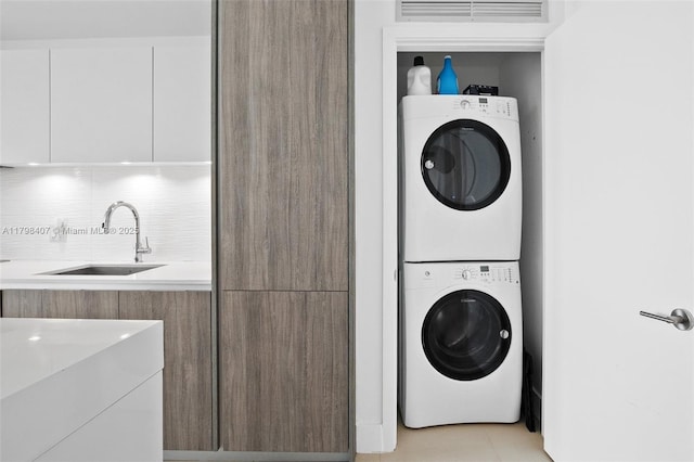 laundry area with stacked washer and clothes dryer and light tile patterned floors