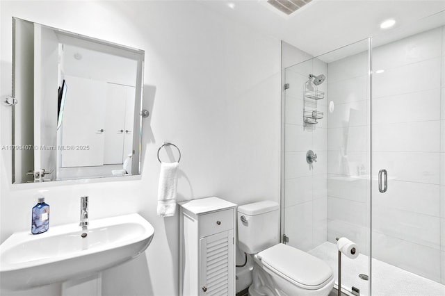 bathroom with a sink, a shower stall, and toilet