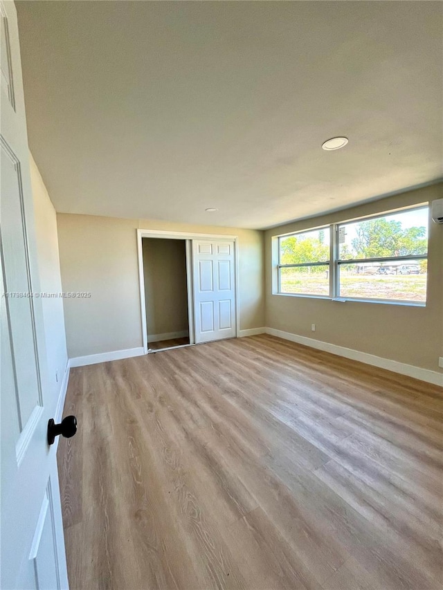 1300 Waite Dr, Fort Myers, FL 33903 - unfurnished bedroom featuring wood finished floors, baseboards, a closet, a wall mounted air conditioner, and recessed lighting