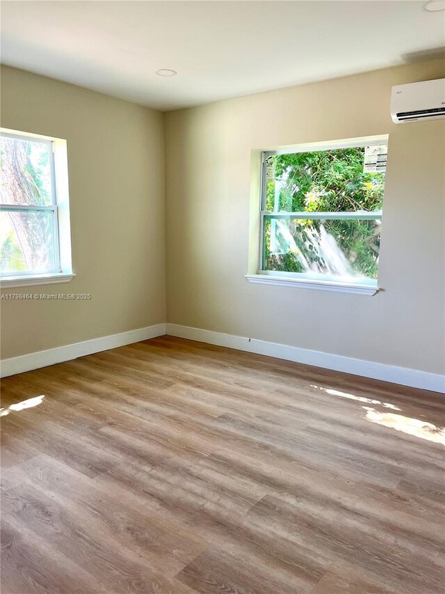 1300 Waite Dr, Fort Myers, FL 33903 - unfurnished room featuring healthy amount of natural light, a wall mounted AC, wood finished floors, and baseboards