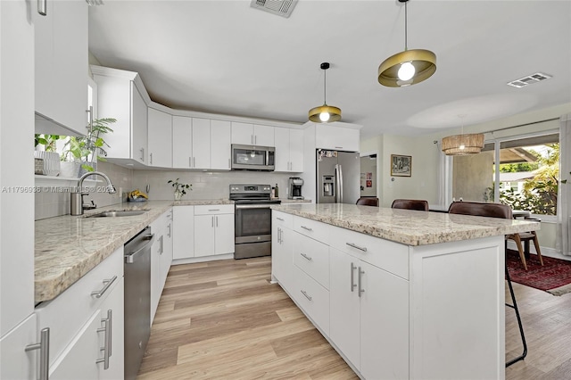 2221 N 46th Ave, Hollywood, FL 33021 - kitchen with stainless steel appliances, a sink, a kitchen island, light wood finished floors, and a breakfast bar