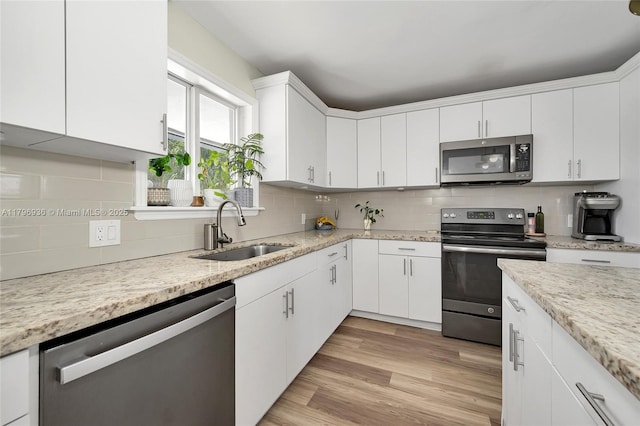 2221 N 46th Ave, Hollywood, FL 33021 - kitchen with stainless steel appliances, a sink, tasteful backsplash, white cabinets, and light wood-style floors