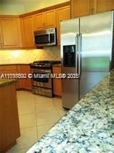 2901 NW 126th Ave Unit 2-325, Sunrise, FL 33323 - kitchen with appliances with stainless steel finishes, brown cabinetry, stone countertops, and light tile patterned flooring
