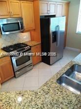 2901 NW 126th Ave Unit 2-325, Sunrise, FL 33323 - kitchen with stainless steel appliances, baseboards, light tile patterned floors, light stone countertops, and a sink