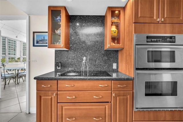 11 Island Ave Unit 512, Miami Beach, FL 33139 - kitchen featuring stainless steel double oven, brown cabinets, decorative backsplash, and light tile patterned flooring