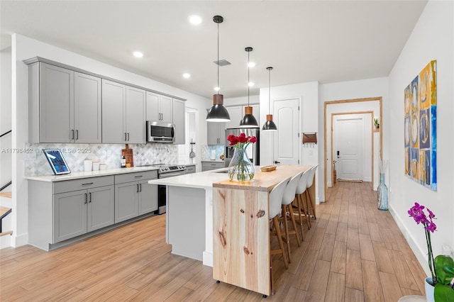 kitchen with stainless steel appliances, gray cabinets, backsplash, light countertops, and recessed lighting