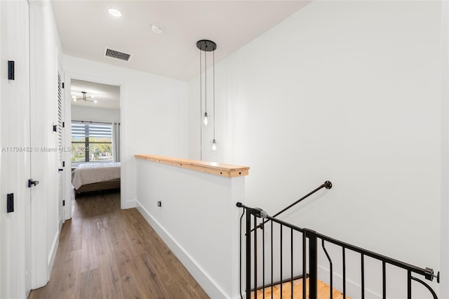 hallway with an upstairs landing, wood finished floors, and baseboards