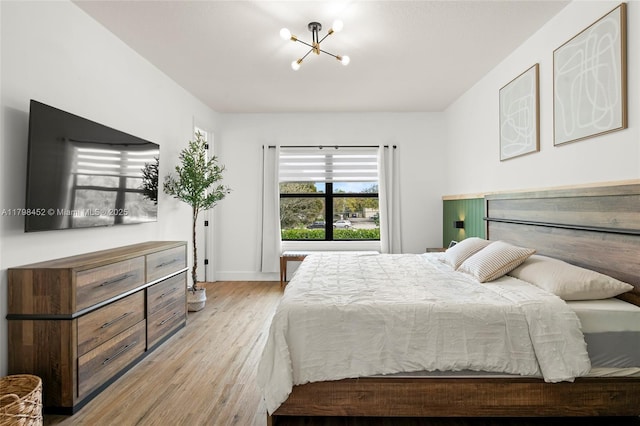 bedroom with a chandelier, wood finished floors, and baseboards