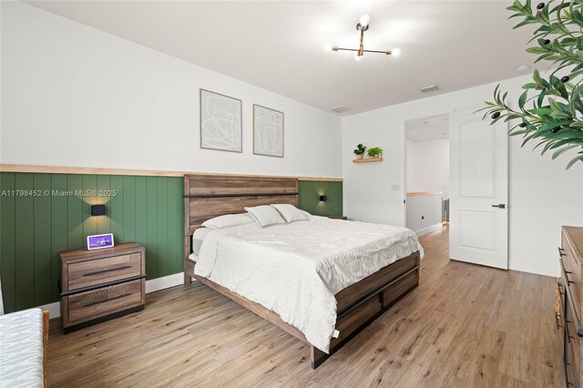 bedroom with wood finished floors and a chandelier