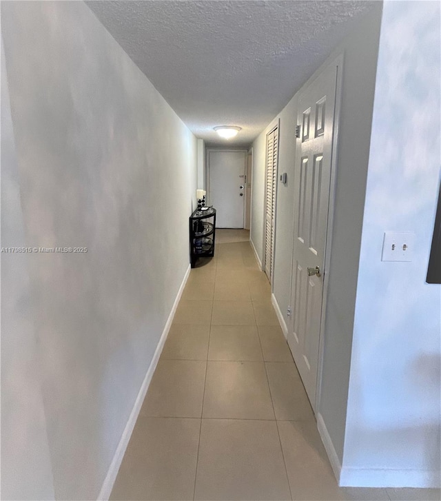 3660 NE 166th St Unit 307, North Miami Beach, FL 33160 - hallway with a textured ceiling, light tile patterned floors, and baseboards