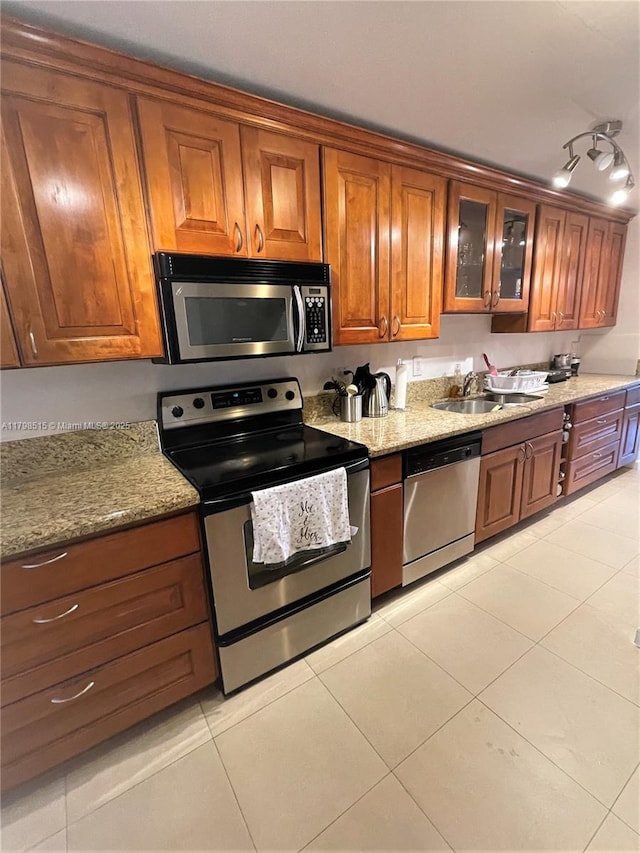 3660 NE 166th St Unit 307, North Miami Beach, FL 33160 - kitchen featuring appliances with stainless steel finishes, a sink, brown cabinets, light tile patterned flooring, and glass insert cabinets