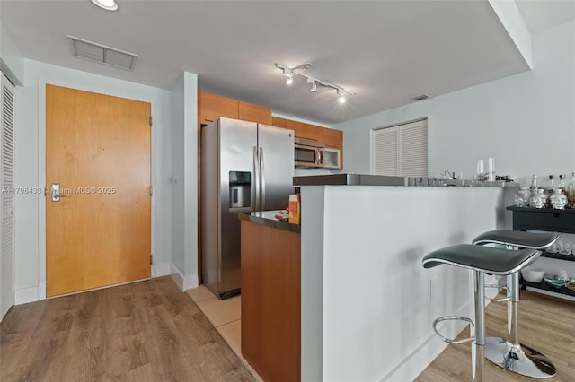 253 NE 2nd St Unit 2201, Miami, FL 33132 - kitchen with appliances with stainless steel finishes, dark countertops, a peninsula, and light wood-type flooring