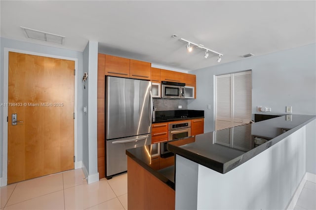 253 NE 2nd St Unit 2201, Miami, FL 33132 - kitchen featuring stainless steel appliances, dark countertops, light tile patterned floors, brown cabinetry, and decorative backsplash