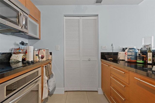 253 NE 2nd St Unit 2201, Miami, FL 33132 - kitchen with appliances with stainless steel finishes, light tile patterned flooring, and dark countertops