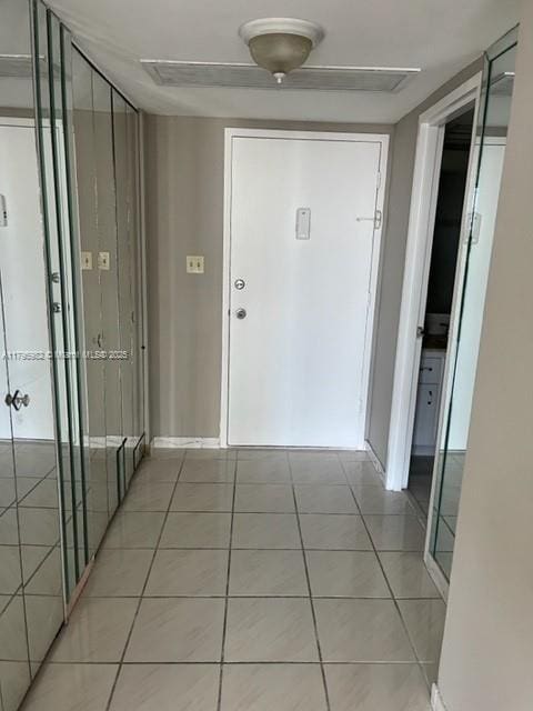 corridor featuring light tile patterned floors and baseboards
