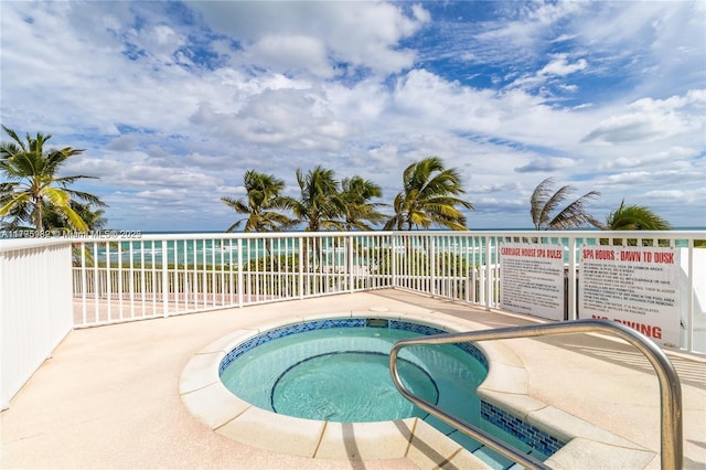 view of pool with fence, a hot tub, and a water view