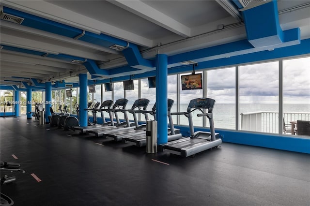 gym with healthy amount of natural light and a water view