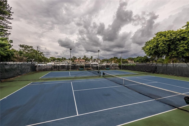 view of tennis court with community basketball court and fence