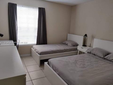 bedroom with light tile patterned floors and baseboards