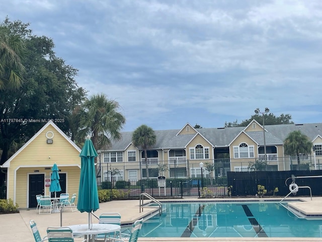 community pool with a patio and fence