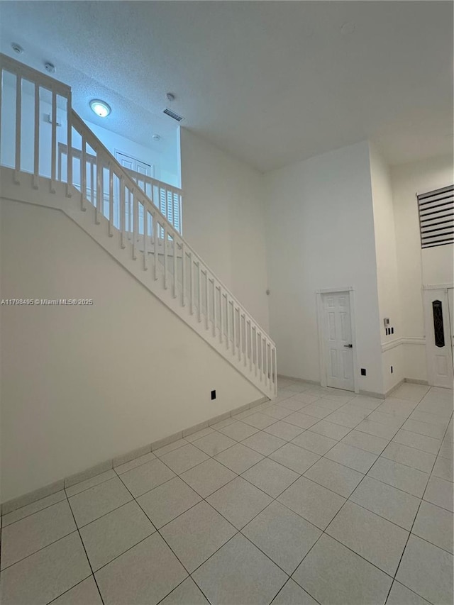 10331 SW 20th Ter, Miami, FL 33165 - unfurnished living room with stairs, tile patterned flooring, baseboards, and a towering ceiling