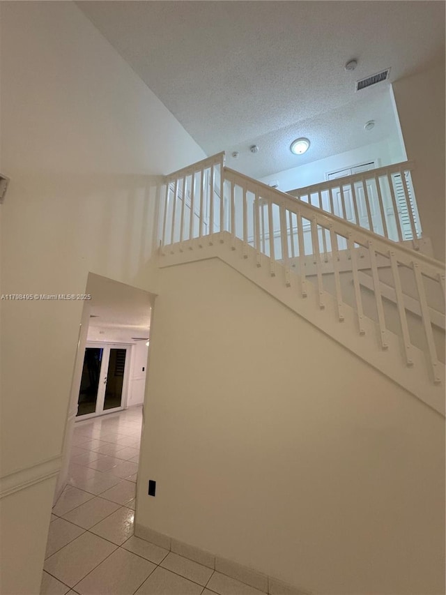 10331 SW 20th Ter, Miami, FL 33165 - stairs featuring tile patterned floors, high vaulted ceiling, baseboards, and a textured ceiling