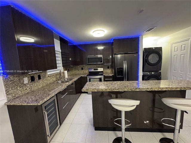 10331 SW 20th Ter, Miami, FL 33165 - kitchen featuring appliances with stainless steel finishes, a sink, estacked washer and dryer, a kitchen bar, and decorative backsplash