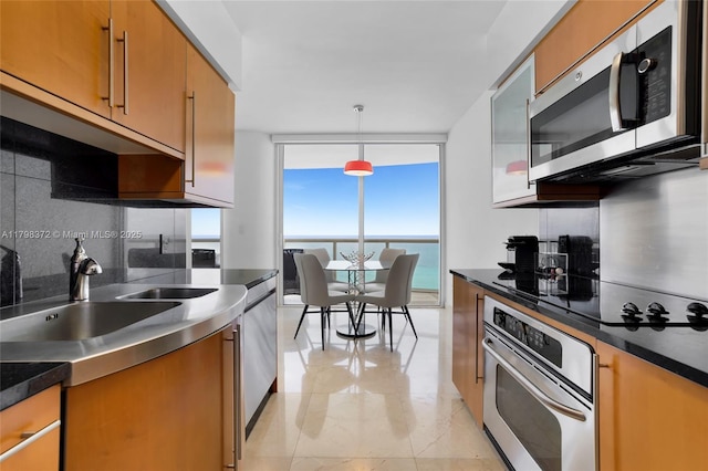 6365 Collins Ave Unit 3202, Miami Beach, FL 33141 - kitchen featuring stainless steel appliances, decorative backsplash, a wall of windows, a sink, and pendant lighting