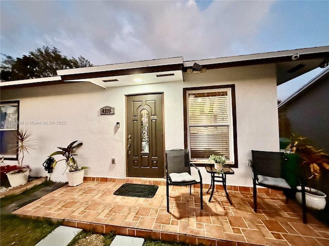 doorway to property with stucco siding and a patio area