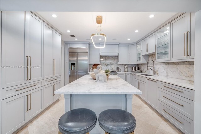 10921 SW 102nd Ct, Miami, FL 33176 - kitchen with stainless steel built in fridge, glass insert cabinets, a sink, decorative backsplash, and light stone countertops