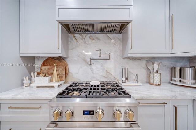 10921 SW 102nd Ct, Miami, FL 33176 - kitchen with stainless steel gas stove, premium range hood, light stone counters, backsplash, and white cabinetry